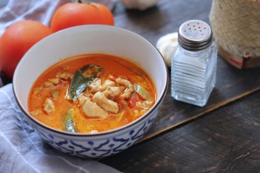 Tayland usulü bir tabakta siyah ahşap bir masada servis edilen tavuk pananjiri..