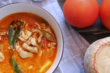 Tayland usulü bir tabakta siyah ahşap bir masada servis edilen tavuk pananjiri..