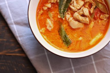 Tayland usulü bir tabakta siyah ahşap bir masada servis edilen tavuk pananjiri..