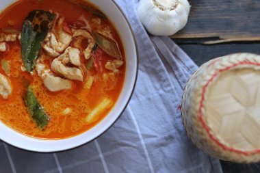 Tayland usulü bir tabakta siyah ahşap bir masada servis edilen tavuk pananjiri..