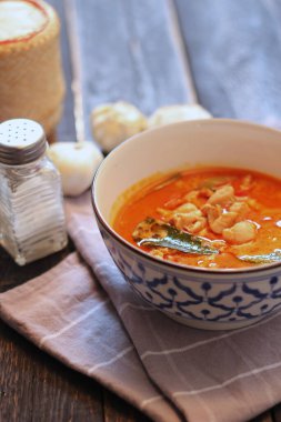 Tayland usulü bir tabakta siyah ahşap bir masada servis edilen tavuk pananjiri..