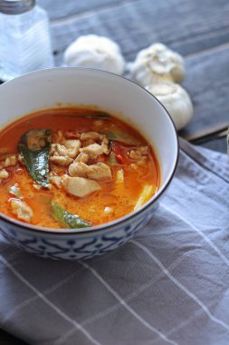 Tayland usulü bir tabakta siyah ahşap bir masada servis edilen tavuk pananjiri..