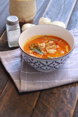 Tayland usulü bir tabakta siyah ahşap bir masada servis edilen tavuk pananjiri..