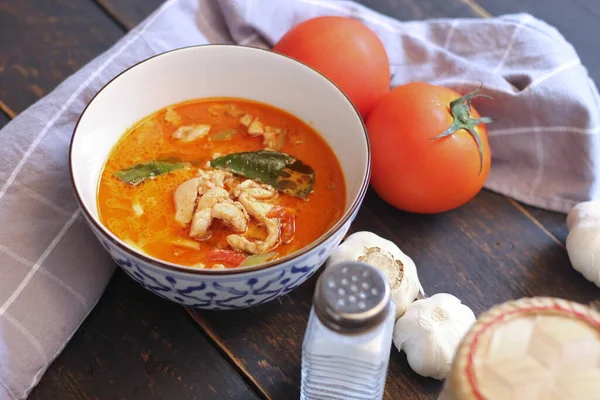 Tayland usulü bir tabakta siyah ahşap bir masada servis edilen tavuk pananjiri..