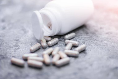 Gri kapsül ve ilaç şişeleri gri masaya yerleştirildi..