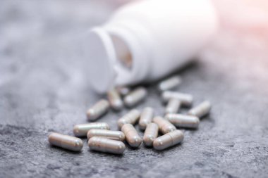 Gri kapsül ve ilaç şişeleri gri masaya yerleştirildi..