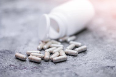 Gri kapsül ve ilaç şişeleri gri masaya yerleştirildi..