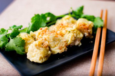 Çin Buharlı Hamur köftesi, ahşap bir masada siyah bir tabakta servis edilir. Kişniş ile birlikte.