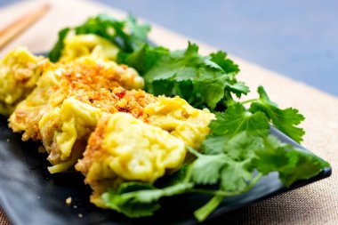 Çin Buharlı Hamur köftesi, ahşap bir masada siyah bir tabakta servis edilir. Kişniş ile birlikte.