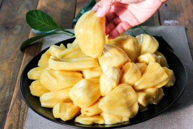 Tayland meyvesi, ahşap bir masada siyah bir tabağa yerleştirilmiş taze meyve..