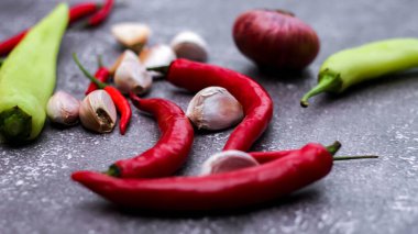 Kırmızı biber ve yeşil biber, gri masaya yayılmış sarımsak mutfakta pişirmeye hazır..