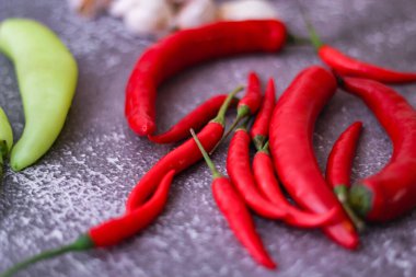 Kırmızı biber ve yeşil biber, gri masaya yayılmış sarımsak mutfakta pişirmeye hazır..
