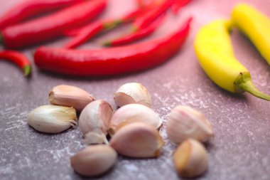 Kırmızı biber ve yeşil biber, gri masaya yayılmış sarımsak mutfakta pişirmeye hazır..