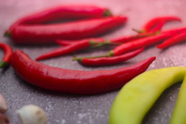 Kırmızı biber ve yeşil biber, gri masaya yayılmış sarımsak mutfakta pişirmeye hazır..