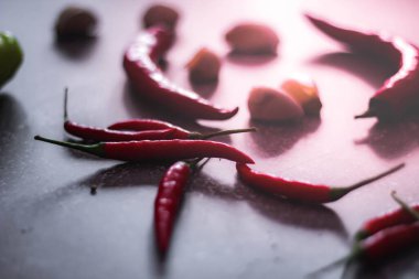 Kırmızı biber ve yeşil biber, gri masaya yayılmış sarımsak mutfakta pişirmeye hazır..