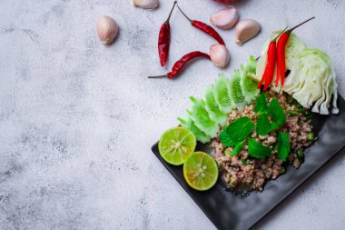 Kıymalı domuz eti, taze sebzelerle servis ediliyor. Kuzeydoğuda popüler bir Tayland yemeği. Taylandca 'da 