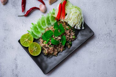 Kıymalı domuz eti, taze sebzelerle servis ediliyor. Kuzeydoğuda popüler bir Tayland yemeği. Taylandca 'da 