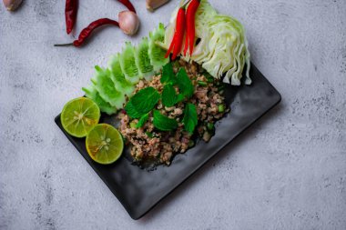 Kıymalı domuz eti, taze sebzelerle servis ediliyor. Kuzeydoğuda popüler bir Tayland yemeği. Taylandca 'da 