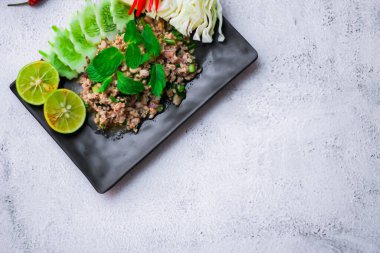 Kıymalı domuz eti, taze sebzelerle servis ediliyor. Kuzeydoğuda popüler bir Tayland yemeği. Taylandca 'da 