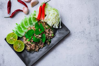 Kıymalı domuz eti, taze sebzelerle servis ediliyor. Kuzeydoğuda popüler bir Tayland yemeği. Taylandca 'da 