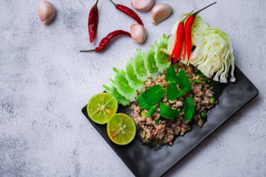 Kıymalı domuz eti, taze sebzelerle servis ediliyor. Kuzeydoğuda popüler bir Tayland yemeği. Taylandca 'da 