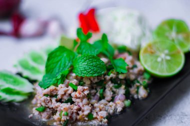 Kıymalı domuz eti, taze sebzelerle servis ediliyor. Kuzeydoğuda popüler bir Tayland yemeği. Taylandca 'da 