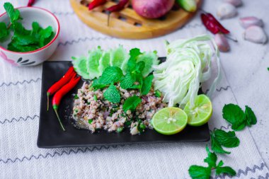Kıymalı domuz eti, taze sebzelerle servis ediliyor. Kuzeydoğuda popüler bir Tayland yemeği. Taylandca 'da 