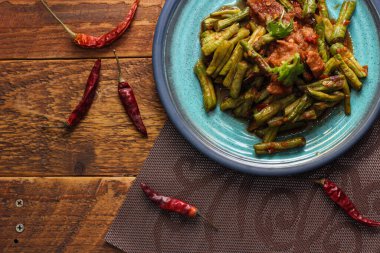 Kızarmış domuz eti ve kırmızı köri ezmesini mavi bir tabakta ahşap bir masada servis edilmiş soya fasulyesiyle karıştır. Tayland 'da bir sokak yemeği..