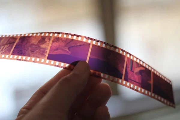 Bir adamın eli 35 mm 'lik bir film tutuyor ve dış ışıkta parlıyor..