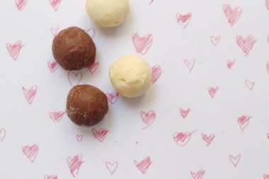 Çikolata topları, pastel boyalardan çizilmiş kalp şeklinde bir arka plana konur..