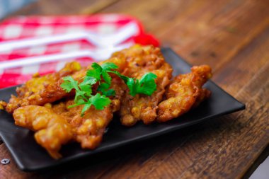 Ahşap bir masa, kaşık ve çatala biber soslu mısır cipsi..