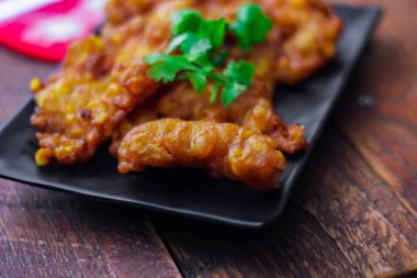 Ahşap bir masa, kaşık ve çatala biber soslu mısır cipsi..