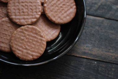 Çikolata aromalı kurabiyeler, ahşap bir masada siyah bir tabakta servis edilir..