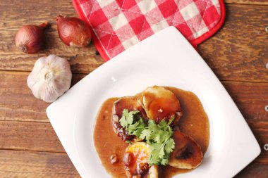 Tahta bir masada kişniş parçacıkları ile servis edilen Tamarind soslu yumurta Taylandlıların yediği popüler bir yerel yemektir..