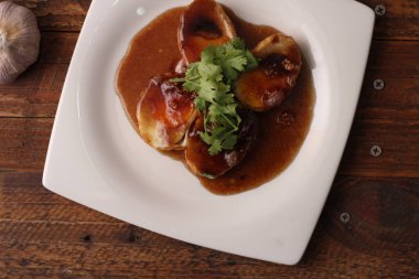 Tahta bir masada kişniş parçacıkları ile servis edilen Tamarind soslu yumurta Taylandlıların yediği popüler bir yerel yemektir..