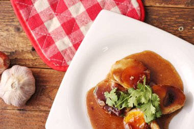 Tahta bir masada kişniş parçacıkları ile servis edilen Tamarind soslu yumurta Taylandlıların yediği popüler bir yerel yemektir..