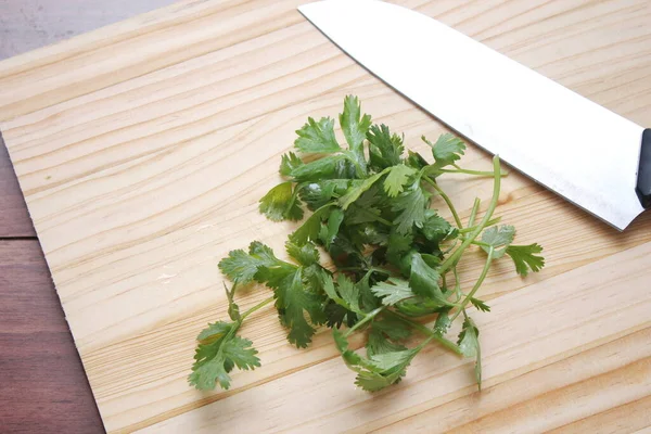 切碎的香菜和小刀放在木制桌子内的木板上 — 图库照片