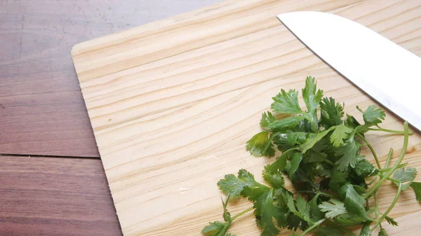 切碎的香菜和小刀放在木制桌子内的木板上 — 图库照片