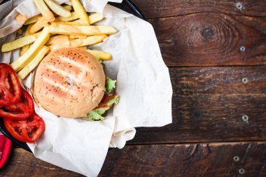 Tahta masada patates kızartması ve domatesle servis edilen ev yapımı hamburgerler. Fast food ve abur cubur.