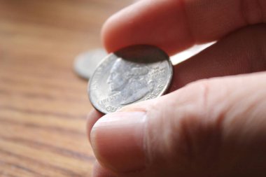 Ahşap zemine serpiştirilmiş 25 sentlik Amerikan parası kaldırıyorum.