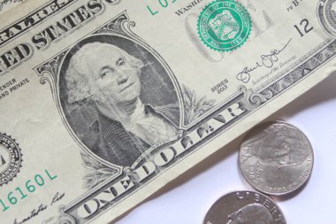 Dolar banknotları ve madeni paralar beyaz bir arkaplana dağılır..