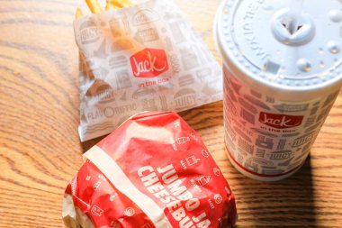 WASHINGTON, ABD - 15 Mart 2022 Hamburgerdeki Jack, kahverengi ahşap bir masada servis edilen patates kızartması ve bardaklar.