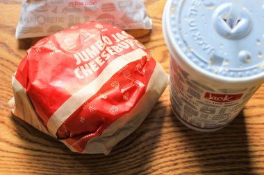 WASHINGTON, ABD - 15 Mart 2022 Hamburgerdeki Jack, kahverengi ahşap bir masada servis edilen patates kızartması ve bardaklar.