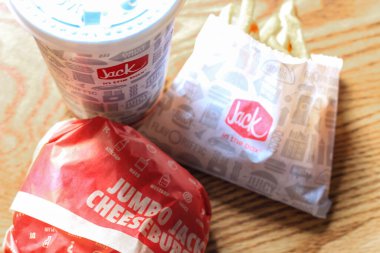 WASHINGTON, ABD - 15 Mart 2022 Hamburgerdeki Jack, kahverengi ahşap bir masada servis edilen patates kızartması ve bardaklar.