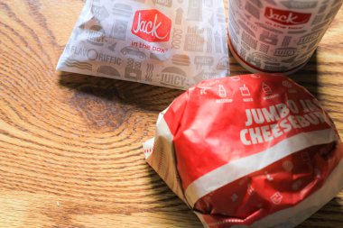 WASHINGTON, ABD - 15 Mart 2022 Hamburgerdeki Jack, kahverengi ahşap bir masada servis edilen patates kızartması ve bardaklar.