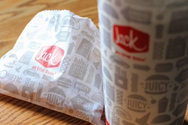 WASHINGTON, ABD - 15 Mart 2022 Hamburgerdeki Jack, kahverengi ahşap bir masada servis edilen patates kızartması ve bardaklar.