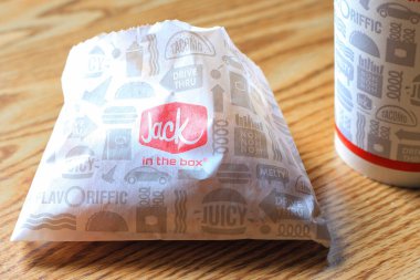 WASHINGTON, ABD - 15 Mart 2022 Hamburgerdeki Jack, kahverengi ahşap bir masada servis edilen patates kızartması ve bardaklar.