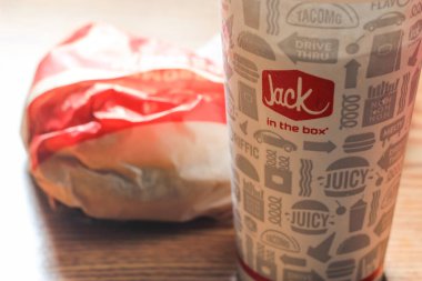 WASHINGTON, ABD - 15 Mart 2022 Hamburgerdeki Jack, kahverengi ahşap bir masada servis edilen patates kızartması ve bardaklar.