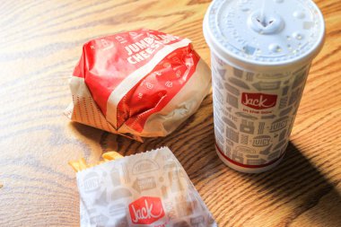 WASHINGTON, ABD - 15 Mart 2022 Hamburgerdeki Jack, kahverengi ahşap bir masada servis edilen patates kızartması ve bardaklar.