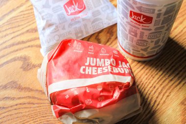 WASHINGTON, ABD - 15 Mart 2022 Hamburgerdeki Jack, kahverengi ahşap bir masada servis edilen patates kızartması ve bardaklar.
